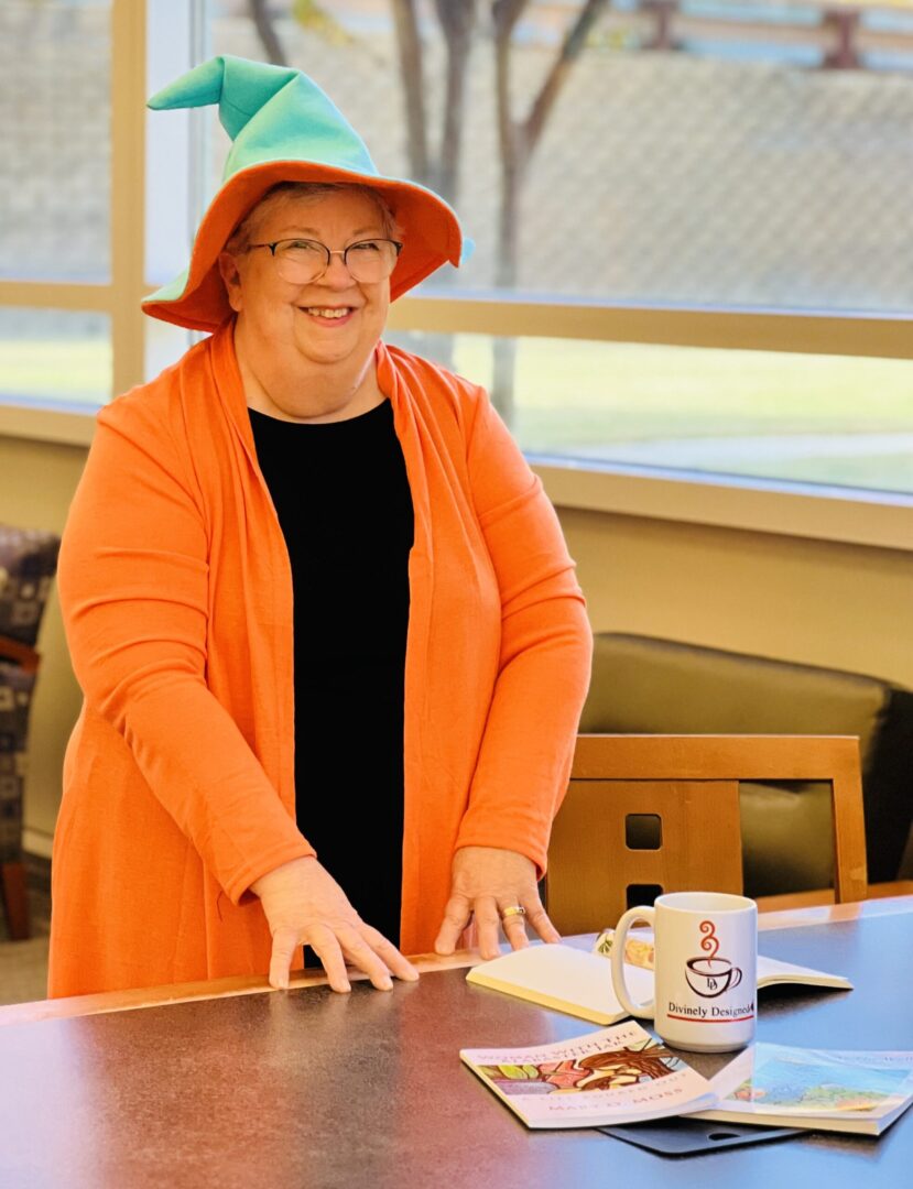 about-page-hero-edited Author Mary Moss in her Word Wizard costume standing behind a table with books